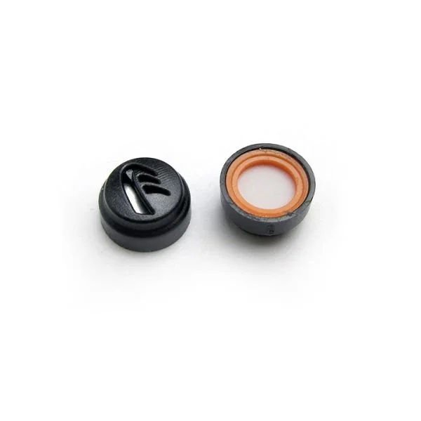Black acoustic earplug filter shown upright and flipped over; the underside has an orange sealing ring around a white membrane